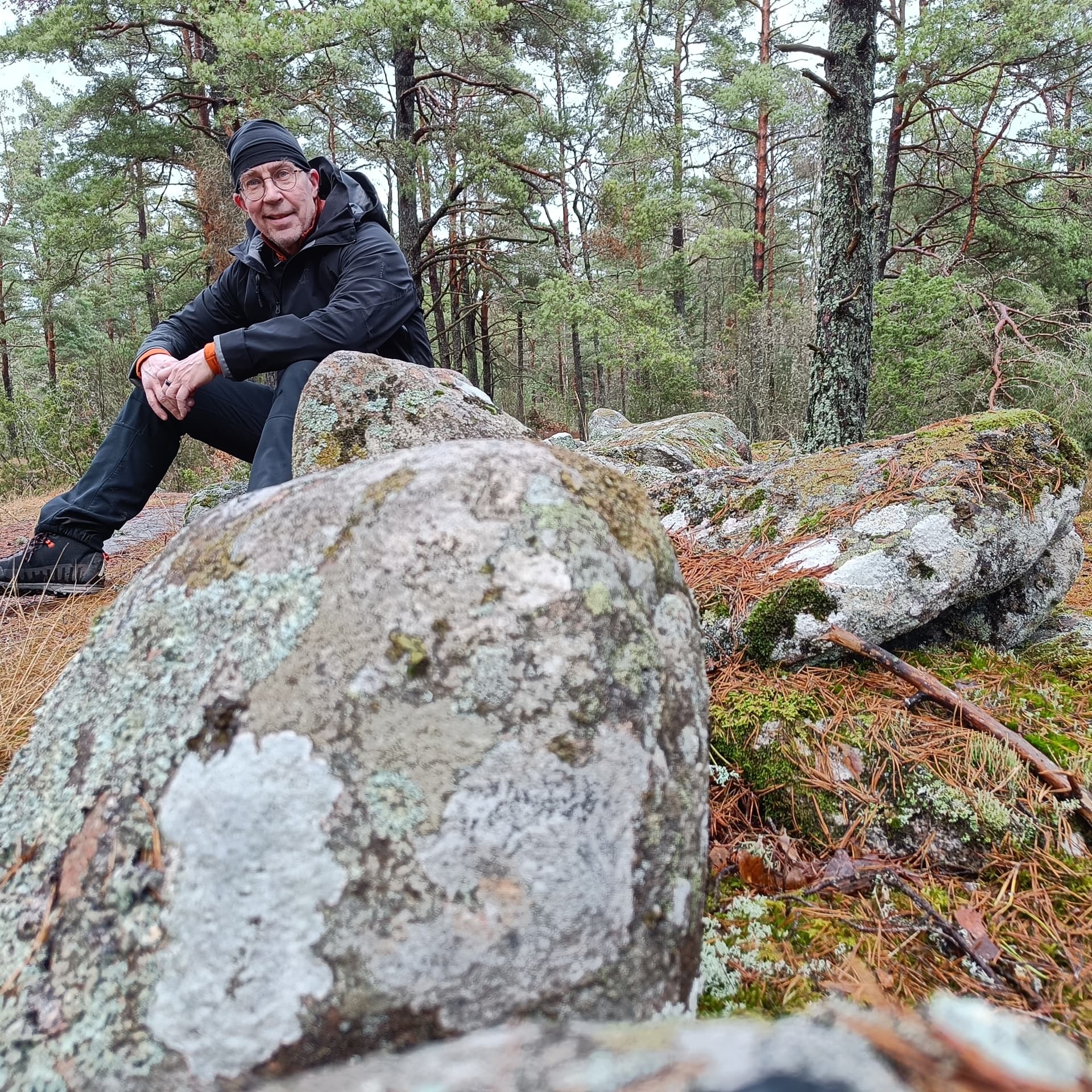 Erik Åstrand sitting among rocks in a Nordic pine forest
